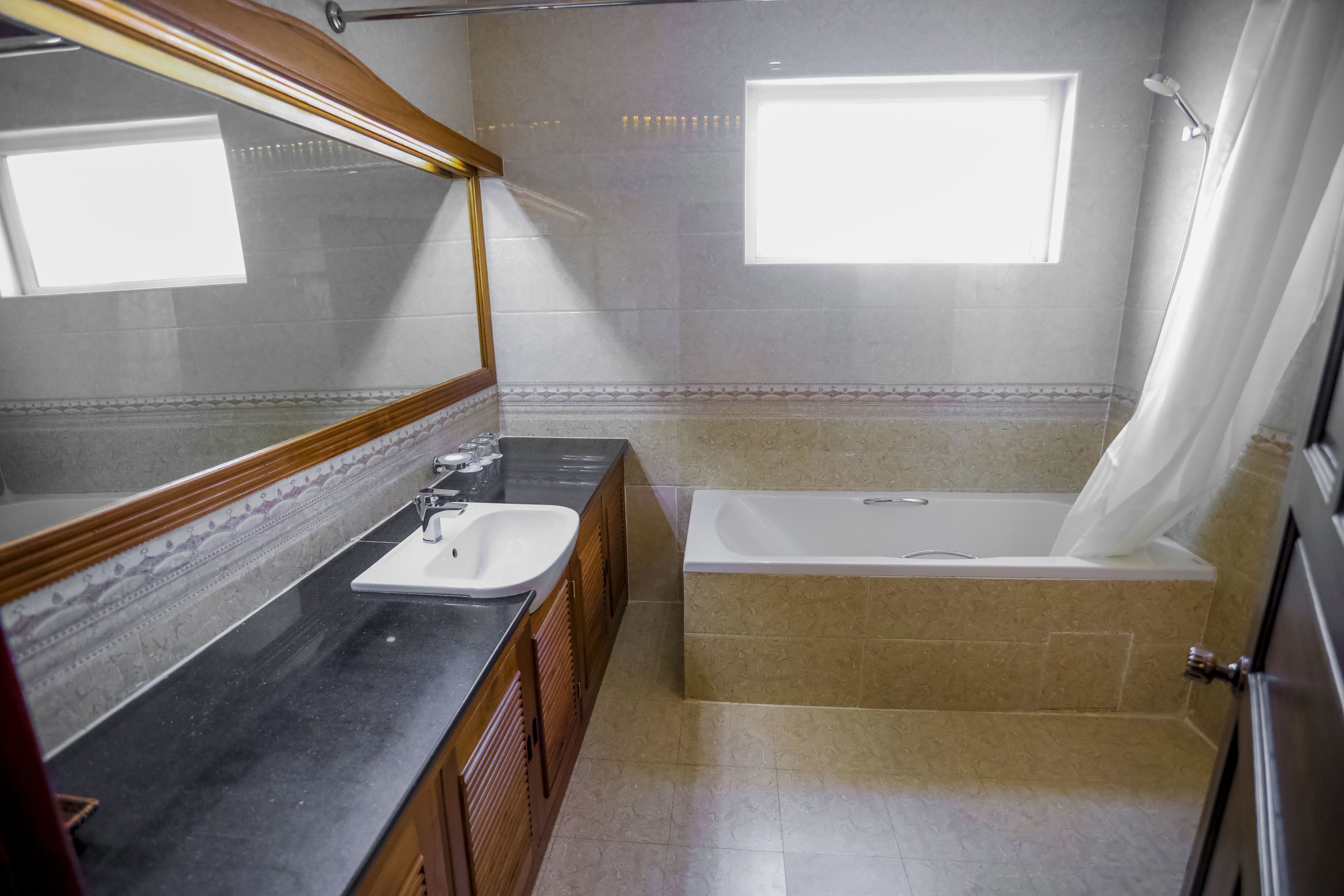 Ein Badezimmer mit Waschbecken, Spiegel, Badewanne und Duschvorhang.