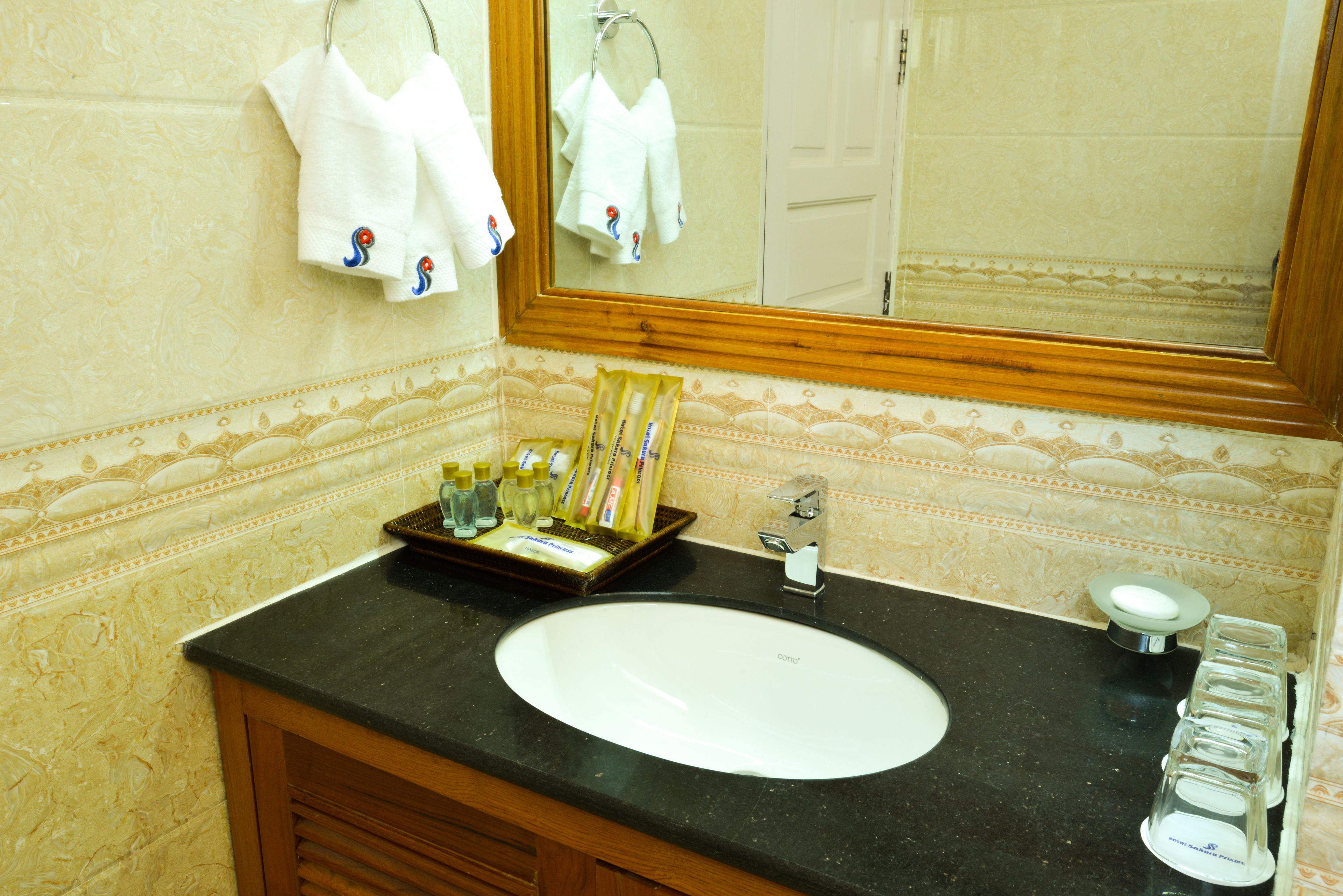 Un bagno con un lavandino bianco, uno specchio e articoli da toilette sul ripiano.
