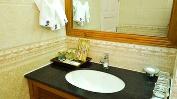 Un bagno con un lavandino bianco, uno specchio e articoli da toilette sul ripiano.