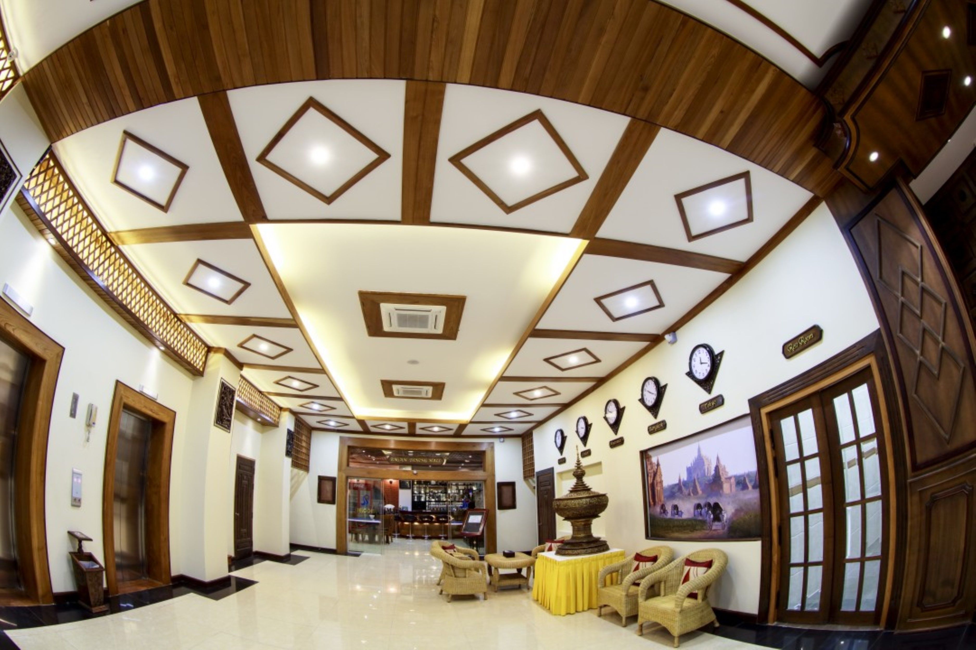 Un hall d’hôtel avec un plafond haut, des lustres et un espace bar.