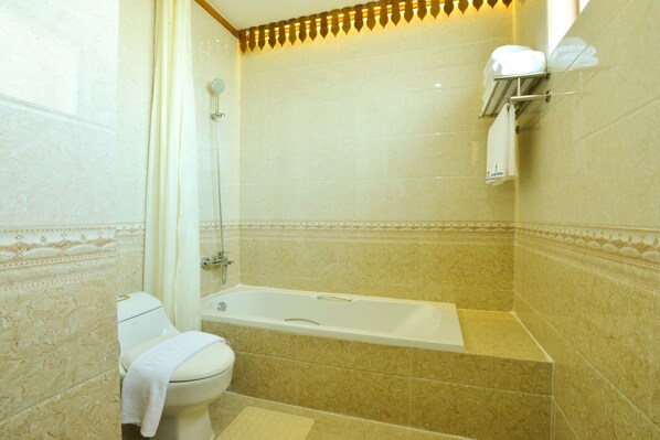 Un baño con bañera, inodoro y perchero para toallas.
