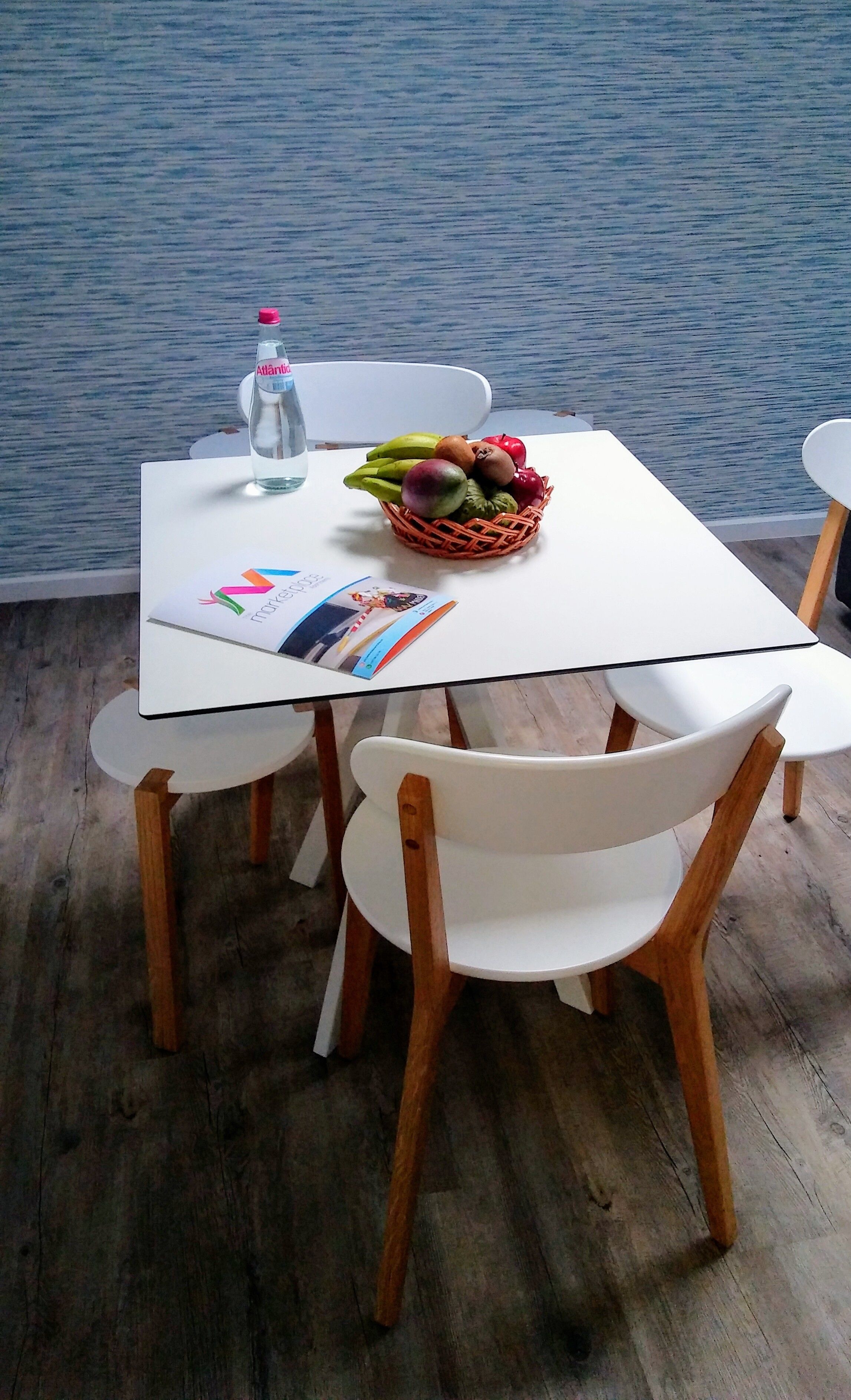 A table with a basket of fruit, a bottle of water, and a magazine.