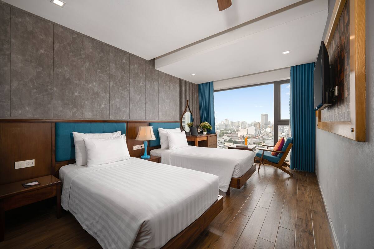 Une chambre d’hôtel avec deux lits, une vue sur la ville, un téléviseur à écran plat et un plancher en bois.