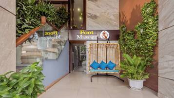A foot massage salon entrance with a wicker chair and potted plants.