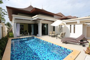 Una piscina al aire libre, sillones reclinables de piscina