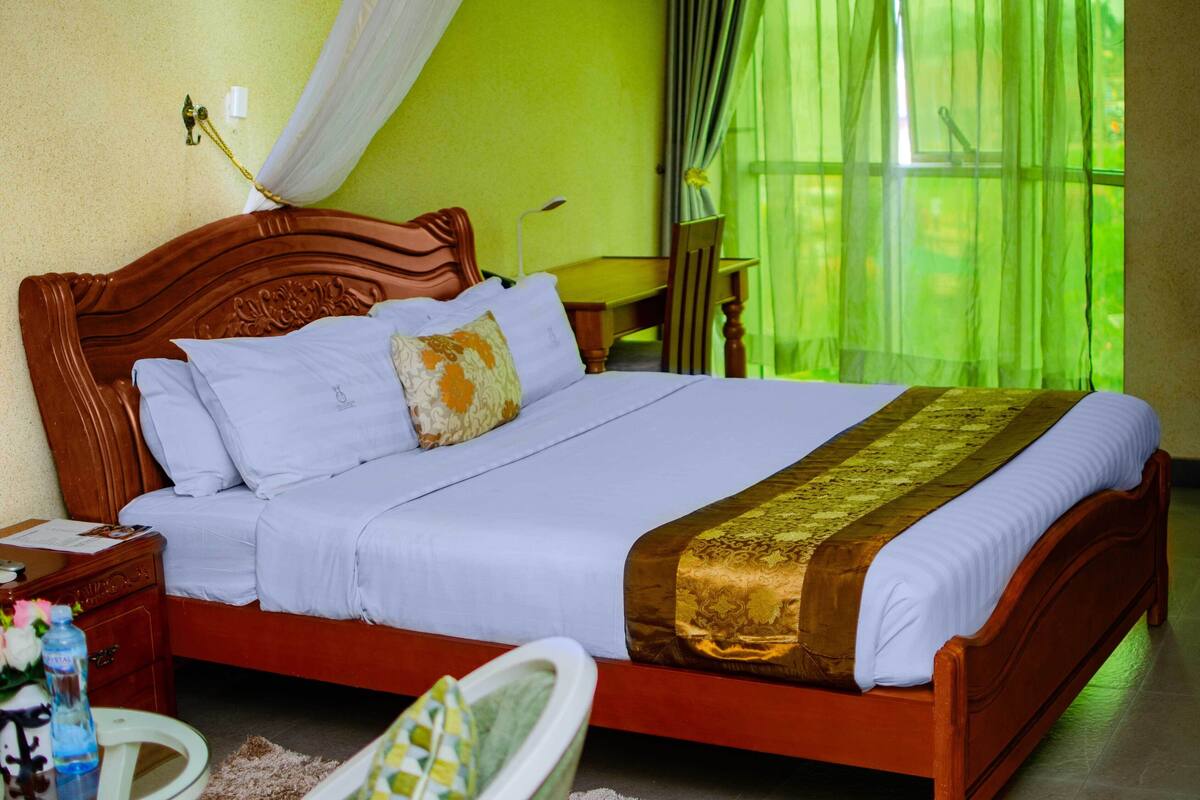 A neatly made bed with a wooden headboard, white linens, and a decorative throw.
