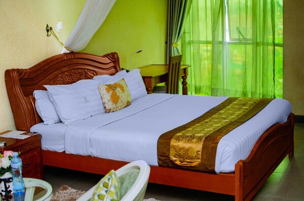 A neatly made bed with a wooden headboard, white linens, and a decorative throw. - Hotel La Grande (Kampala)