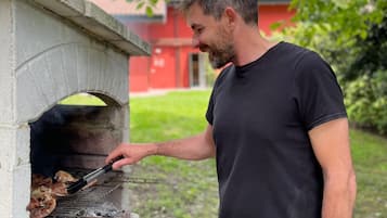 Ein Mann grillt Fleisch in einem Outdoor-Ziegelofen.