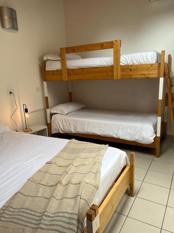 A bunk bed room with a single bed on the left and a bunk bed on the right. - Ostello Casa Rossa (Laveno Mombello)