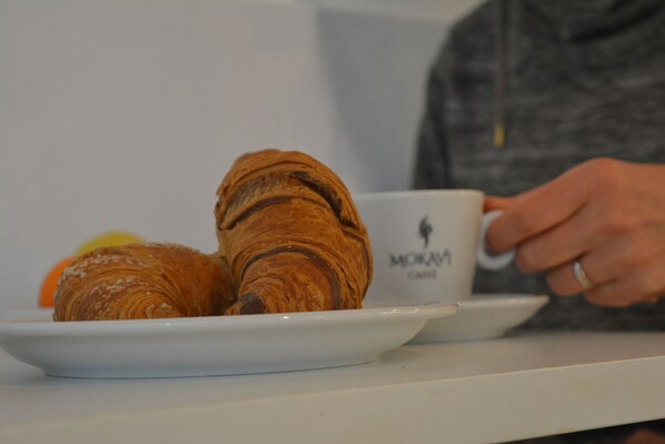 Un plato con cruasanes y una taza con logotipo sobre una mesa.