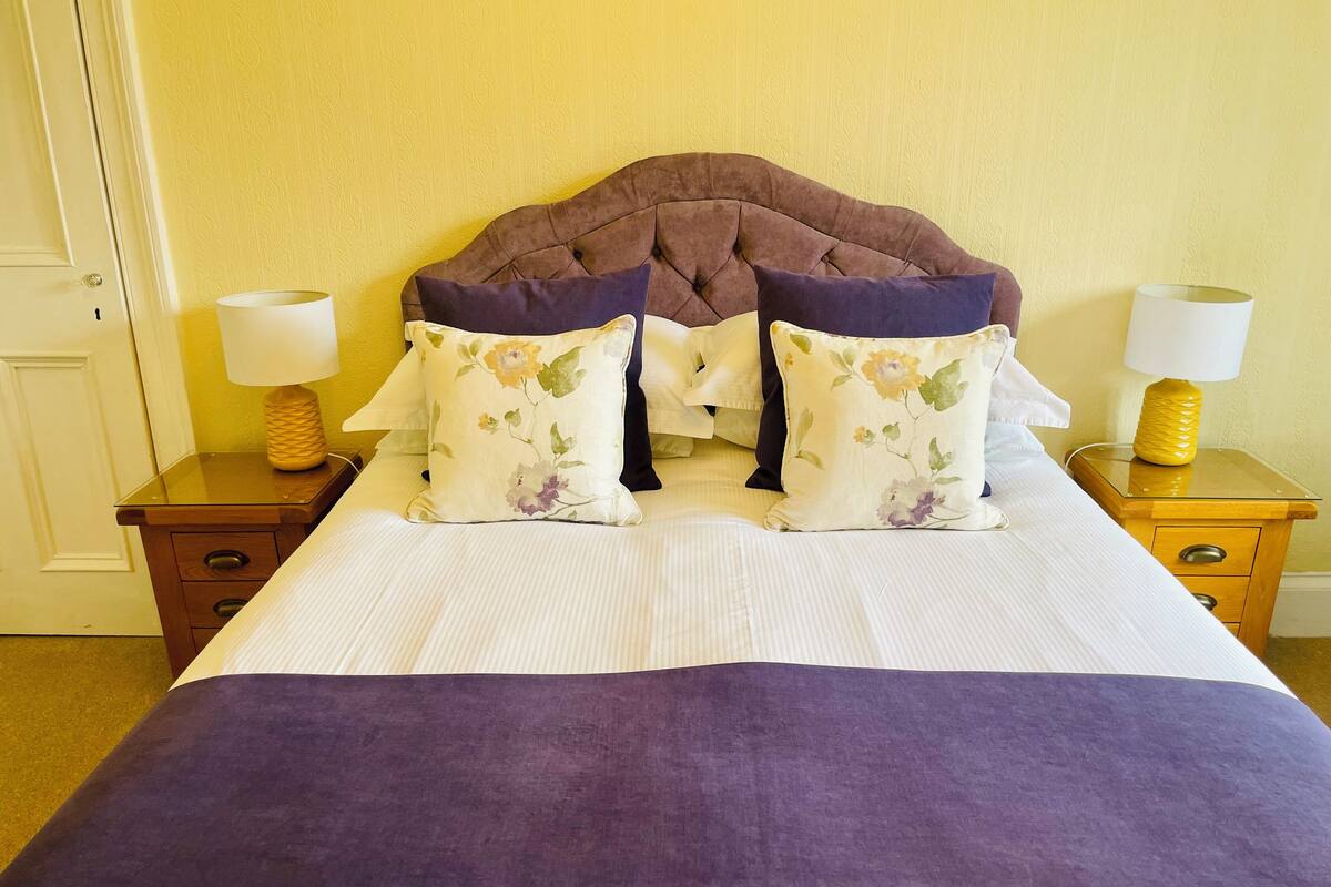 A bed with a tufted headboard, two nightstands with lamps, and a floral pillow.