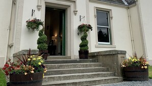 A building with a white facade, a circular window above the entrance, and a traditional pitched roof. - West Plean House (Stirling)
