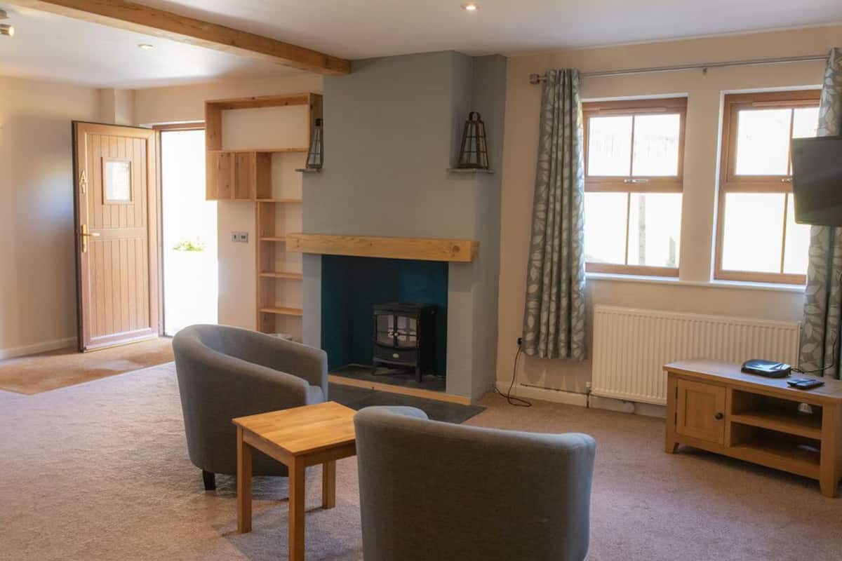 A cozy living room with a fireplace, comfortable seating, and a view of the outdoors.