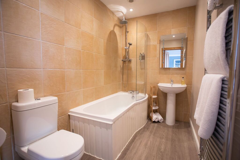 A bathroom with a bathtub, toilet, sink, and a mirror.