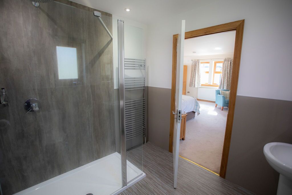 A modern bathroom with a glass shower enclosure, a visible towel rack, and a sink.
