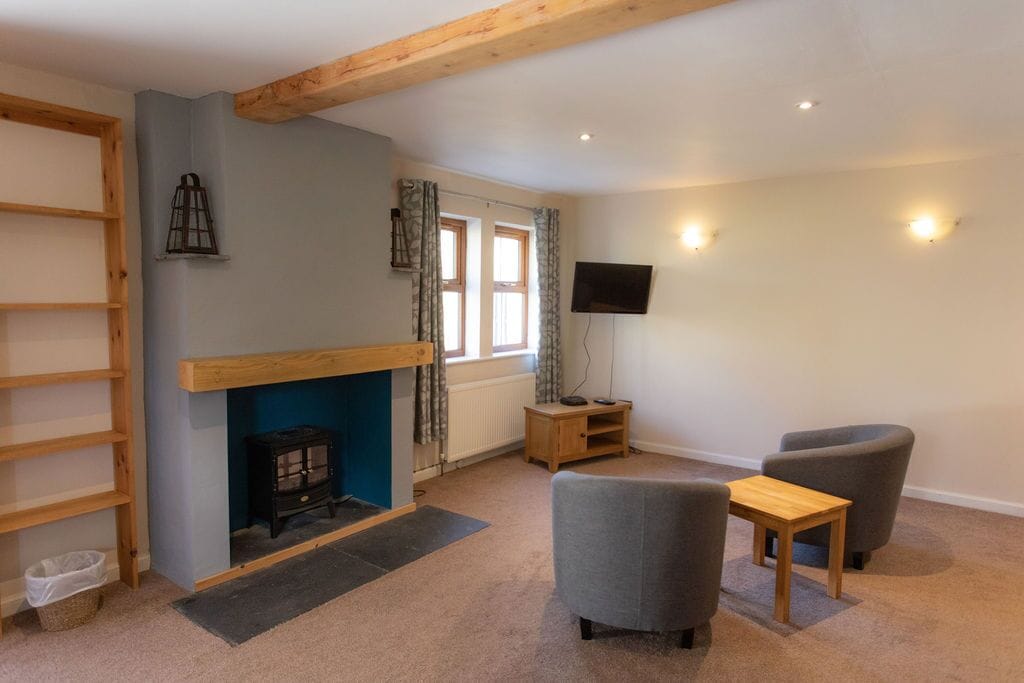 A cozy living room with a fireplace, a TV mounted on the wall, and a comfortable seating area.