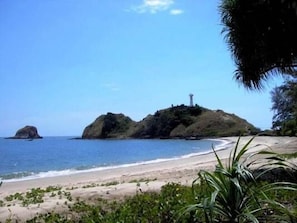 A beach with clear blue water, sandy shore, and rocky outcrops. - AHA Lanta Cozy Hostel (Ko Lanta)