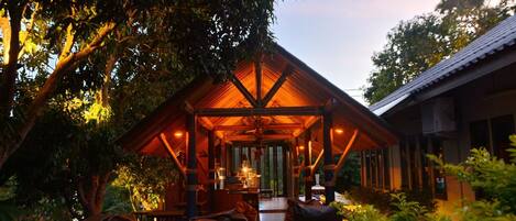 A wooden cabin with a covered porch, surrounded by trees.