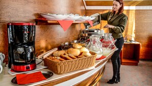 A buffet setup with a coffee maker, bread basket, and various food items on a counter. - Hotel Krone (Freilassing)