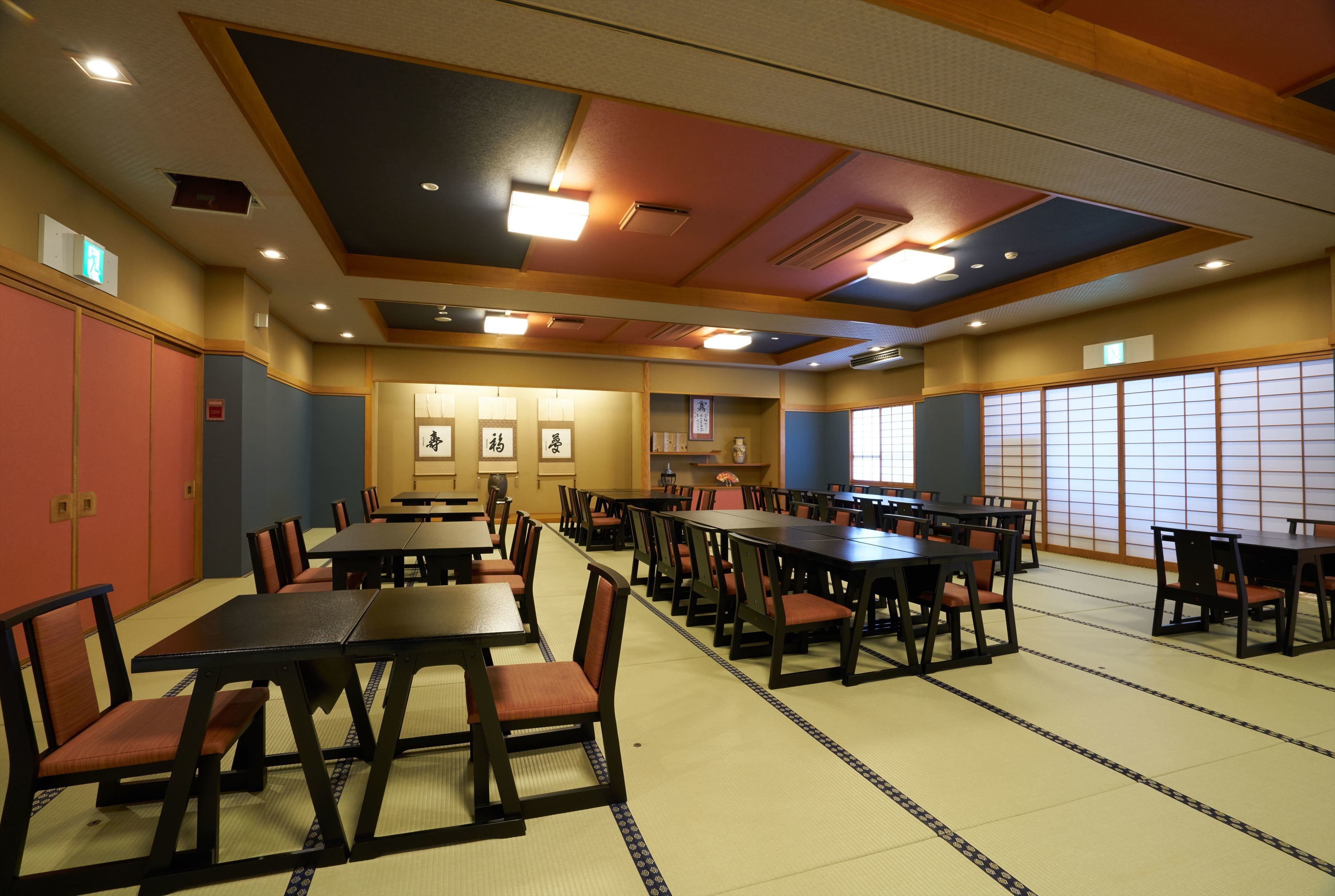 A traditional Japanese-style room with tatami flooring, wooden tables and chairs, and shoji screens.