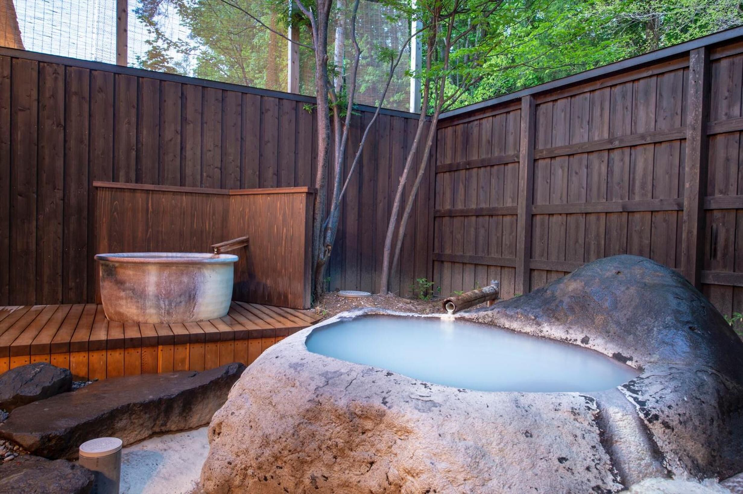 A hot tub in a wooden outdoor setting with a wooden deck and a wooden fence.