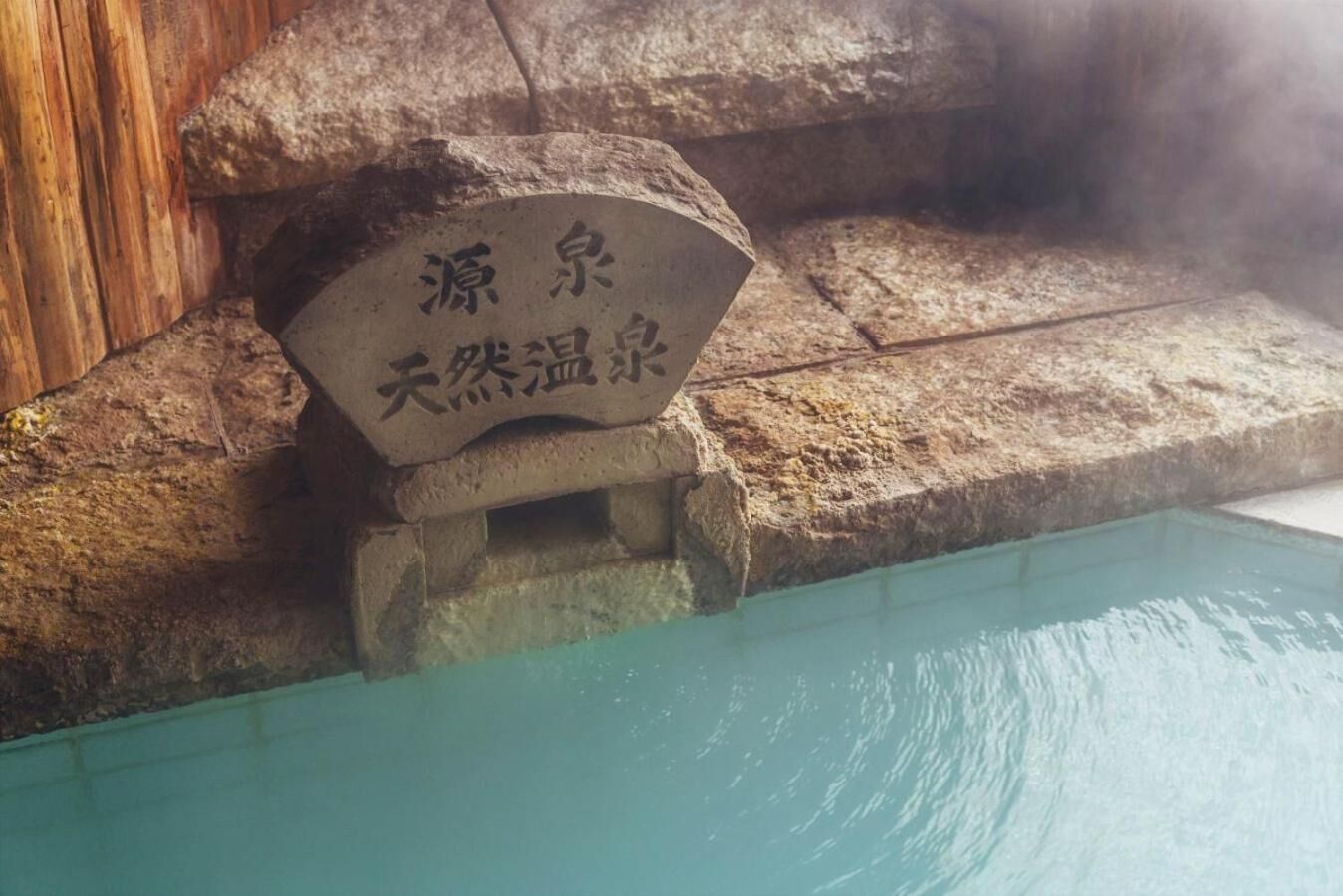 A stone sign with Chinese characters next to a pool.