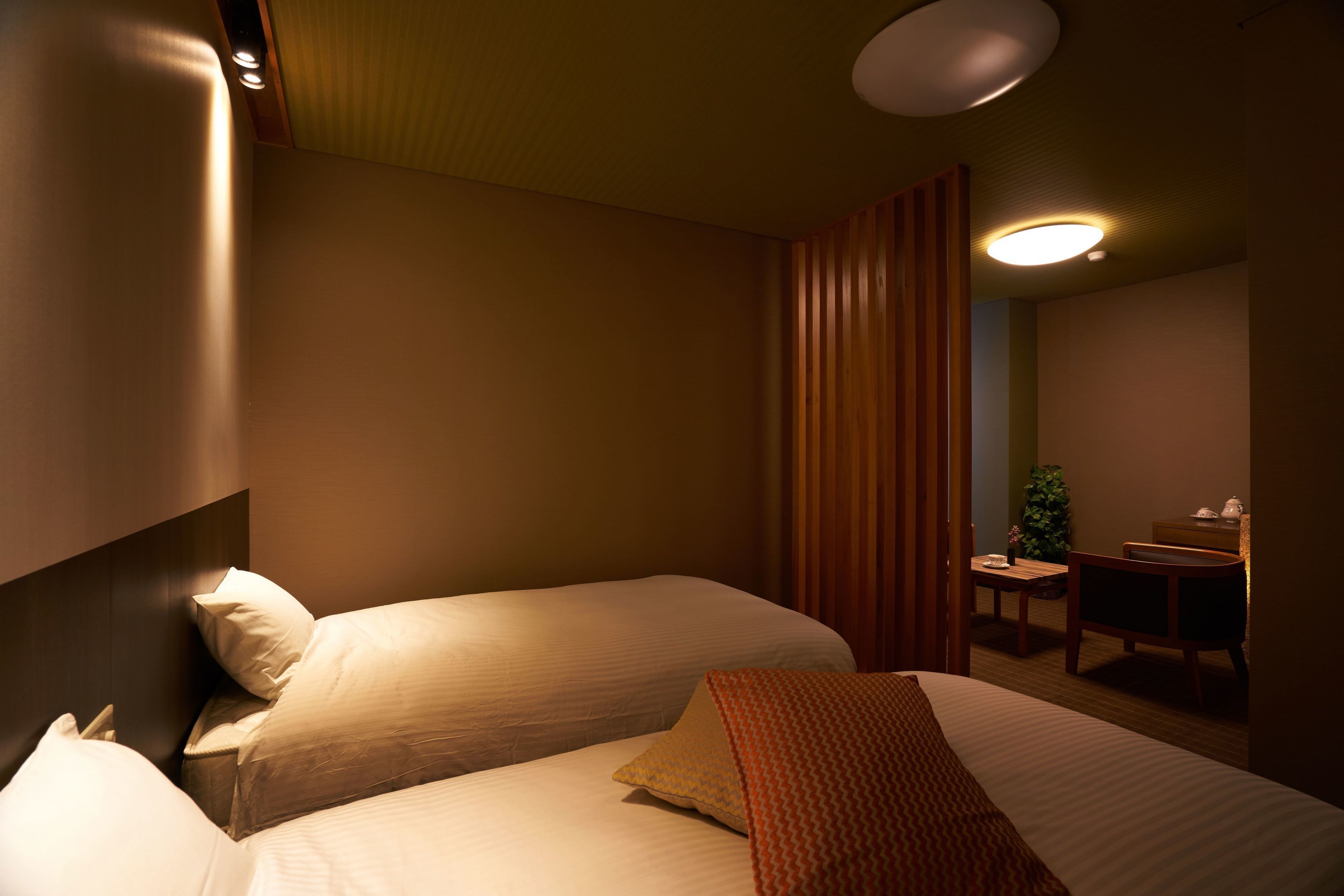 A hotel room with two beds, a desk, and a chair.