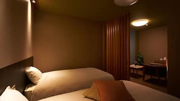 A hotel room with two beds, a desk, and a chair.
