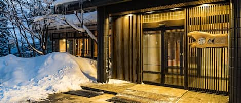 A traditional Japanese building with a wooden exterior and sliding doors, surrounded by snow.