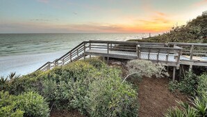 A wooden boardwalk leading to a beach with a sunset view.