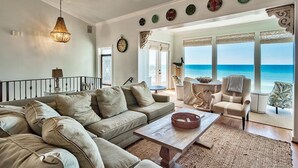 A spacious living room with a large sofa, a coffee table, and a view of the ocean.