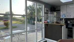 Une cuisine moderne dotée de grandes fenêtres, offrant une vue sur un parking, et d’un comptoir équipé de tout le nécessaire.