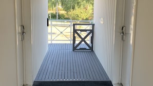 Un couloir menant à un balcon, avec un paillasson noir à l’entrée.