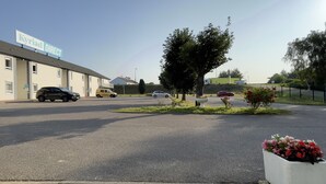 Un parking avec, au fond, un bâtiment sur lequel on peut lire l'inscription « Kyriad DIRECT ».