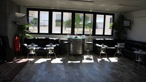 A modern living room with a large window, a glass coffee table, and black leather sofas. - Atmos Luxe Navigli Hostel & Rooms (Milan)