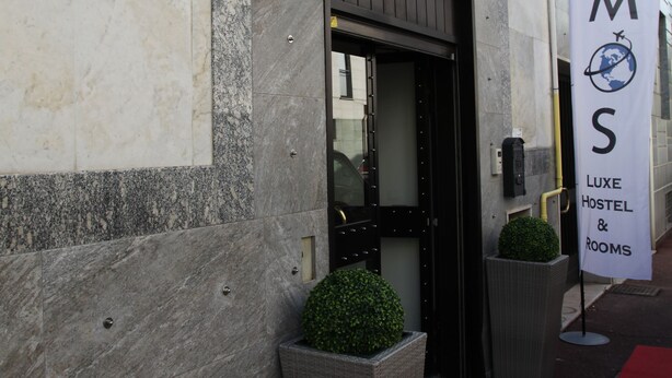 A building entrance with a sign for ATMS LUXE HOSTEL & ROOMS. - Atmos Luxe Navigli Hostel & Rooms (Milan)