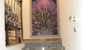 A staircase with granite steps leading to a door, a decorative metal railing on the left, and a framed landscape painting above the door. - Atmos Luxe Navigli Hostel & Rooms (Milan)