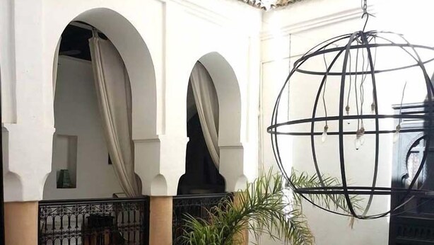 A courtyard with arches, a hanging light fixture, and potted plants.