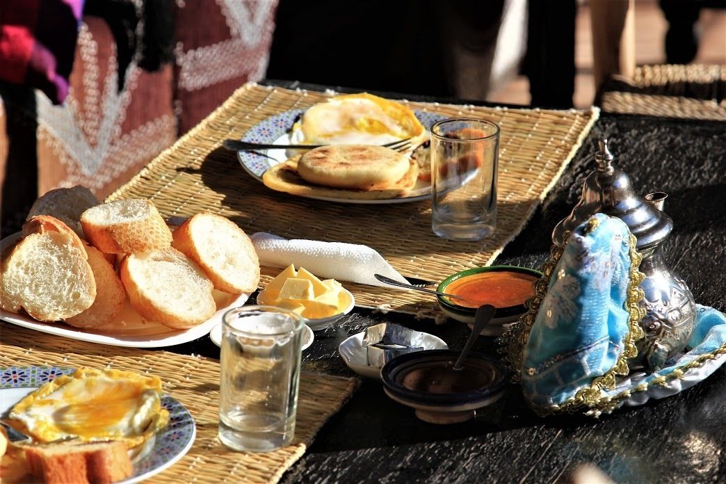 A table with bread, a plate with a sandwich, a glass of water, and a decorative blue item.