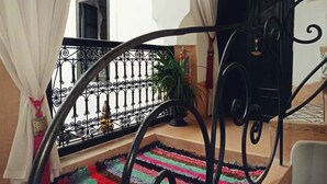 A staircase with a black wrought iron railing, a colorful striped rug, and a potted plant on the landing.