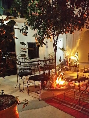 Un comedor interior con una mesa y sillas, un pequeño hogar y plantas en macetas.