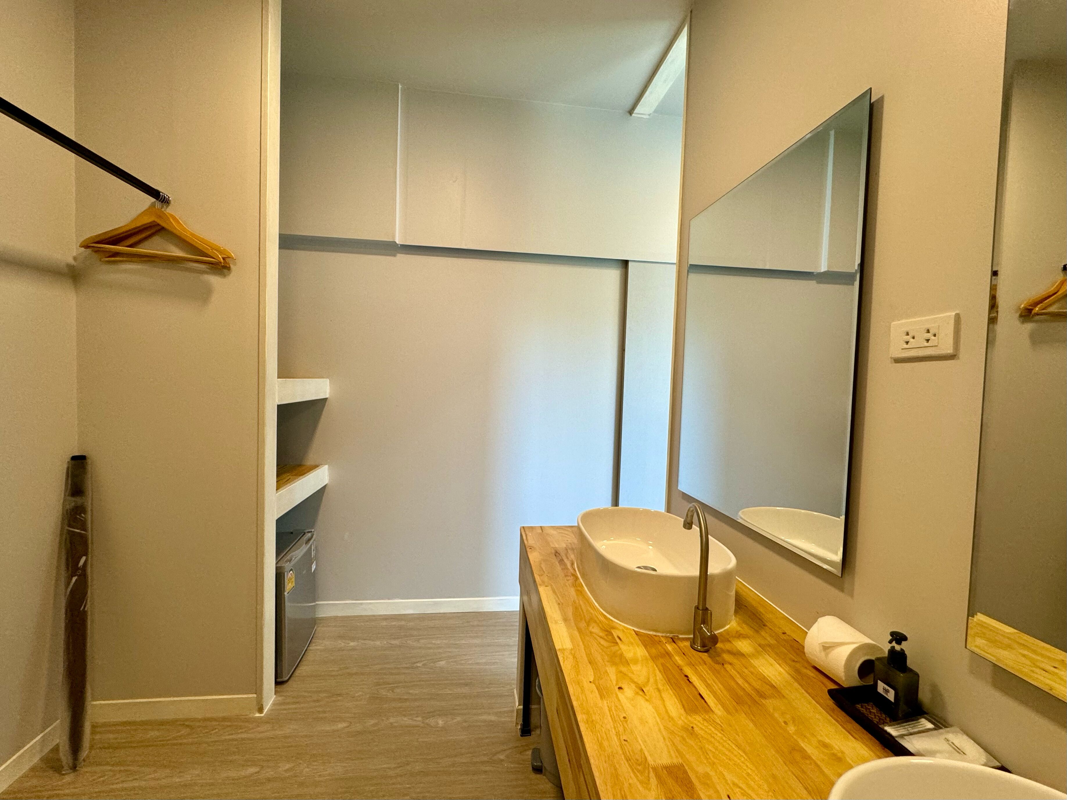 A modern bathroom with a wooden vanity, a large mirror, and a white sink.