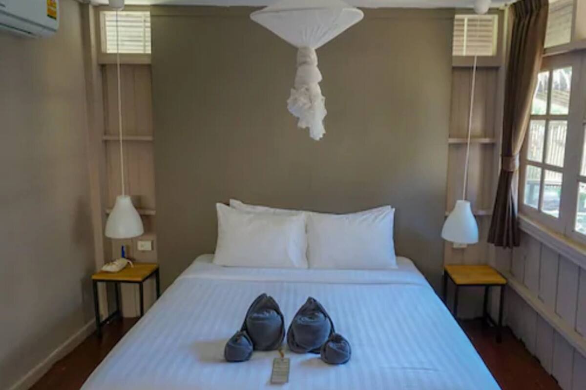 Een hotelkamer met een groot bed, twee nachtkastjes en een hanglamp.
