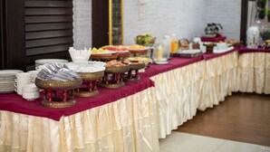 A buffet table with various dishes and utensils, covered with a red cloth and a white drape. - PhoomThai Garden (Phrae)