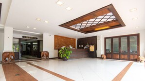 A spacious lobby with a wooden reception desk, a large potted plant, and a wooden elephant sculpture. - PhoomThai Garden (Phrae)