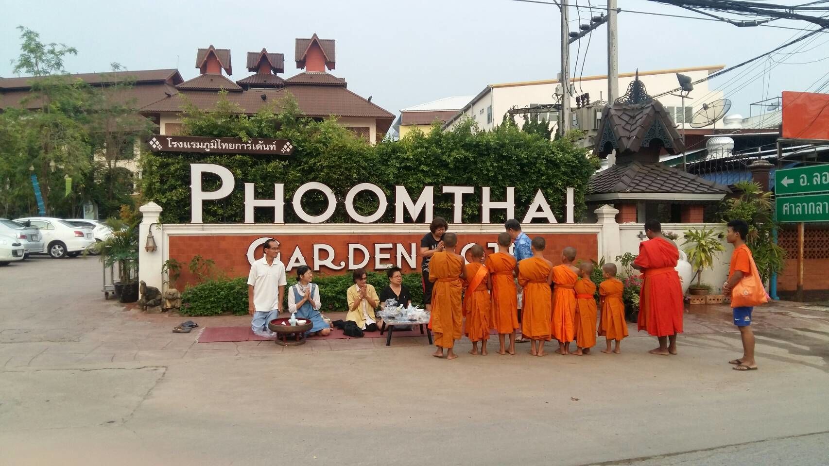 Señal de Phoomthai Garden con un grupo de monjes delante.