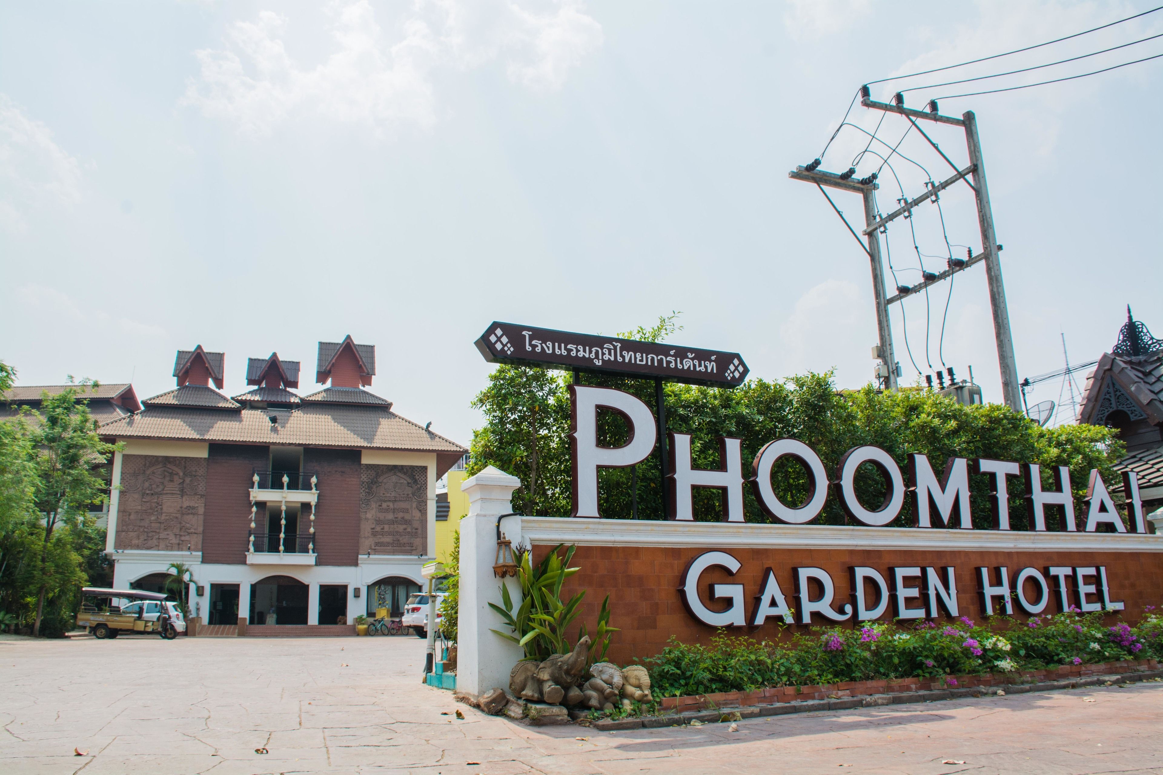A sign for Phoomthai Garden Hotel with a clear view of the building's entrance and a parking area.