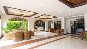 A spacious lobby with wicker furniture, a tiled floor, and a view of the outdoors. - PhoomThai Garden (Phrae)