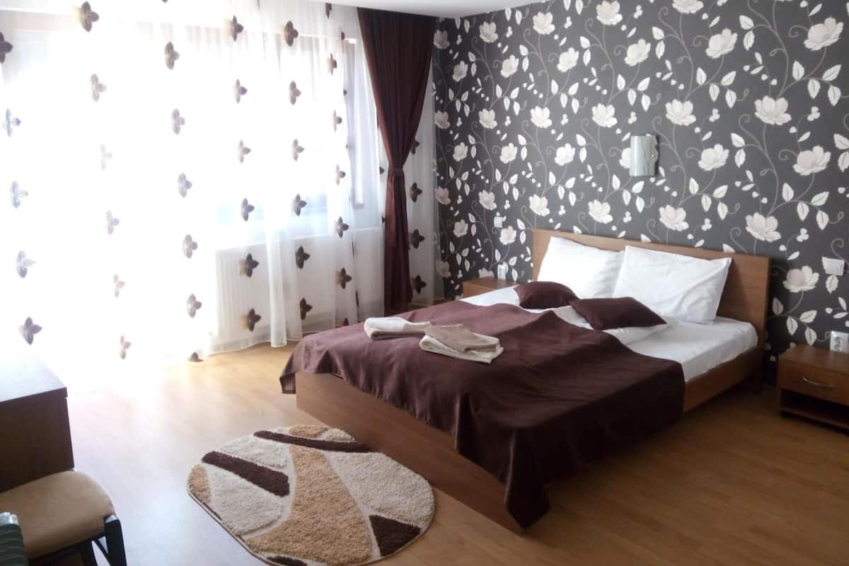 A hotel room with a bed, a desk, and a chair.