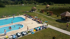 Un espace piscine comprenant plusieurs bassins, des chaises longues et un kiosque.
